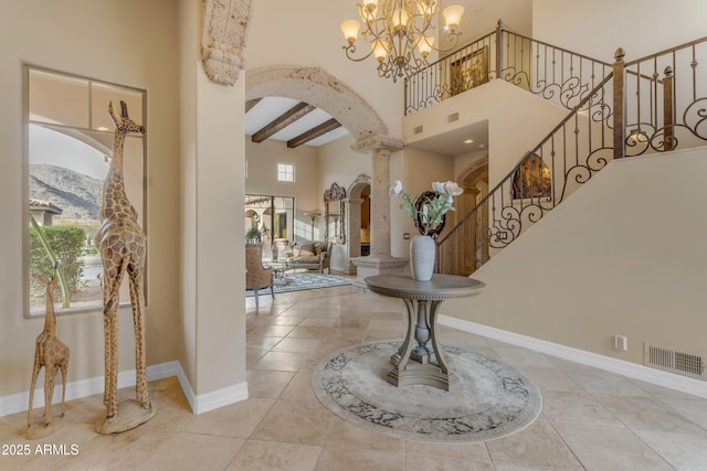 foyer with beam ceiling, arched walkways, a high ceiling, tile patterned flooring, and stairs