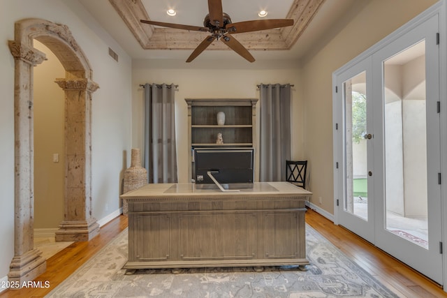 home office with a tray ceiling, french doors, visible vents, and light wood-style flooring