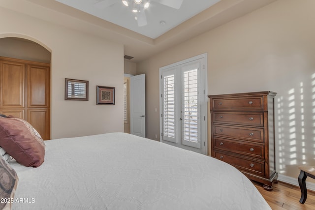 bedroom featuring ceiling fan, french doors, wood finished floors, arched walkways, and access to outside