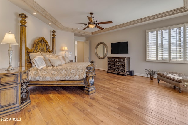 bedroom featuring a tray ceiling, baseboards, and wood finished floors