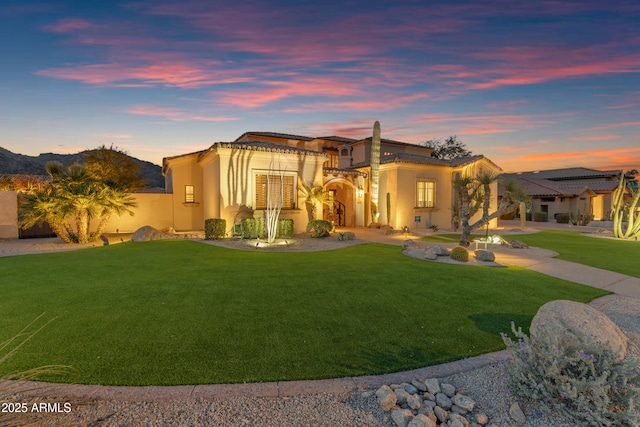 view of front of property featuring stucco siding, driveway, a lawn, and a balcony