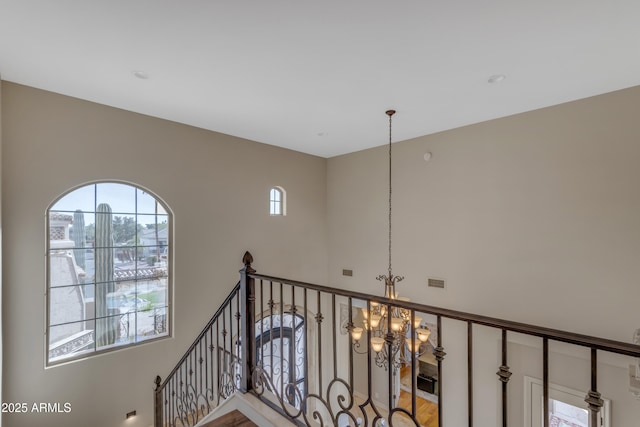 corridor with an inviting chandelier, an upstairs landing, and visible vents