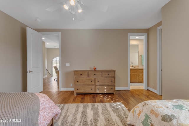 bedroom with baseboards, ceiling fan, ensuite bathroom, and light wood finished floors