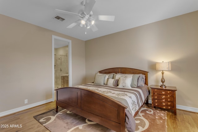 bedroom featuring a ceiling fan, wood finished floors, visible vents, baseboards, and ensuite bath