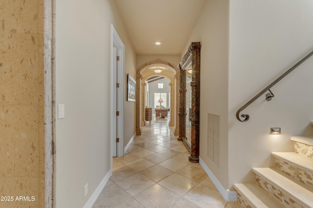 hall featuring visible vents, baseboards, stairs, light tile patterned floors, and arched walkways