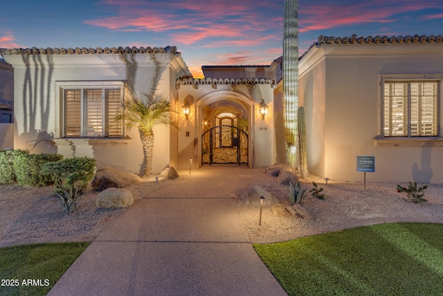 view of front of home featuring a gate, driveway, and stucco siding