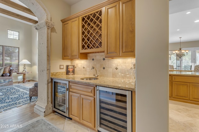 bar with indoor wet bar, decorative backsplash, wine cooler, and a sink