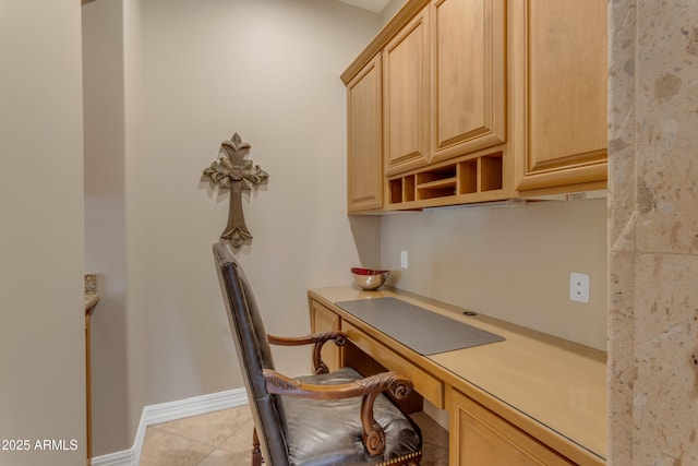 unfurnished office featuring light tile patterned floors, baseboards, and built in desk