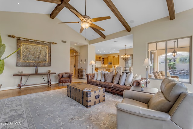 living room with light wood finished floors, visible vents, baseboards, beamed ceiling, and ceiling fan with notable chandelier