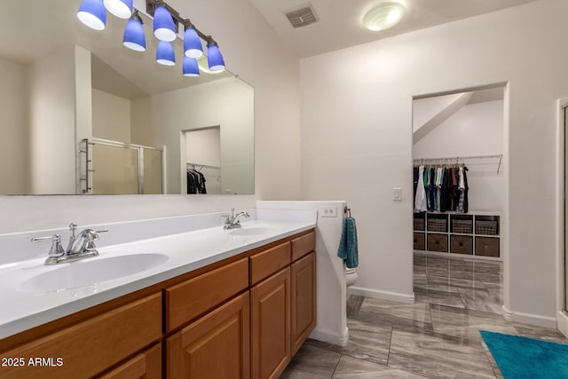 full bathroom featuring a stall shower, visible vents, a sink, and a walk in closet