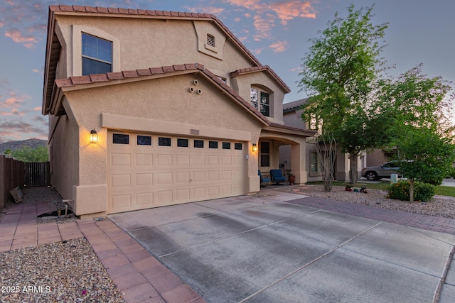 view of front of home featuring concrete driveway, stucco siding, fence, and an attached garage
