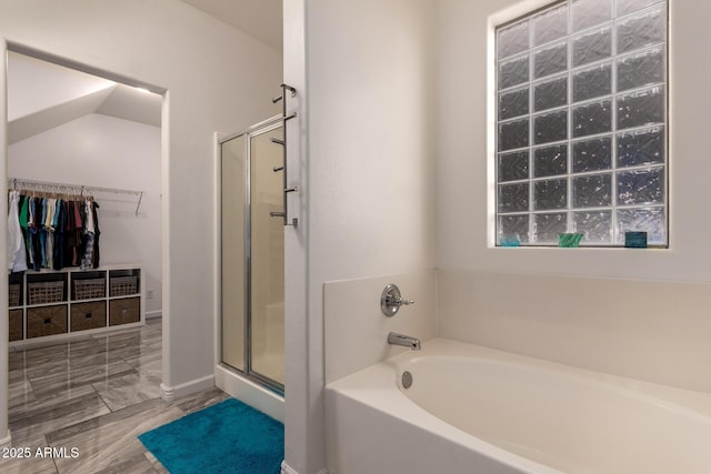 bathroom featuring a shower stall, a garden tub, and a walk in closet