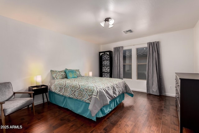 bedroom with baseboards, visible vents, and dark wood finished floors