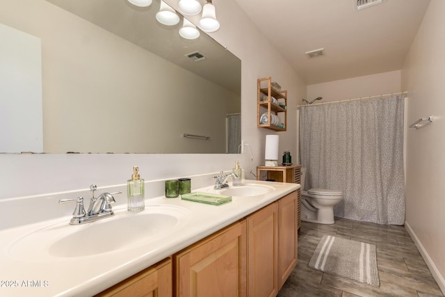 full bathroom featuring toilet, visible vents, a sink, and wood finished floors