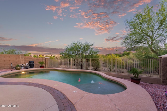 pool at dusk featuring a patio area, a fenced in pool, and a fenced backyard