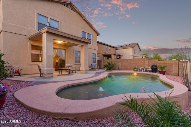 pool at dusk featuring a fenced backyard, a patio area, and a fenced in pool