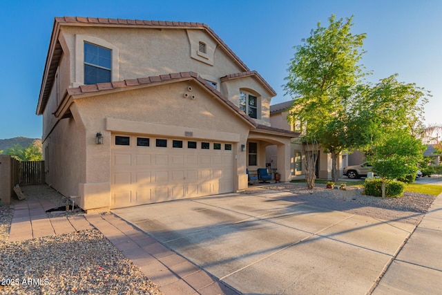 view of front facade featuring driveway, stucco siding, a tile roof, and fence