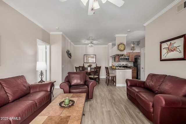 living room with ornamental molding, ceiling fan, and light wood-type flooring