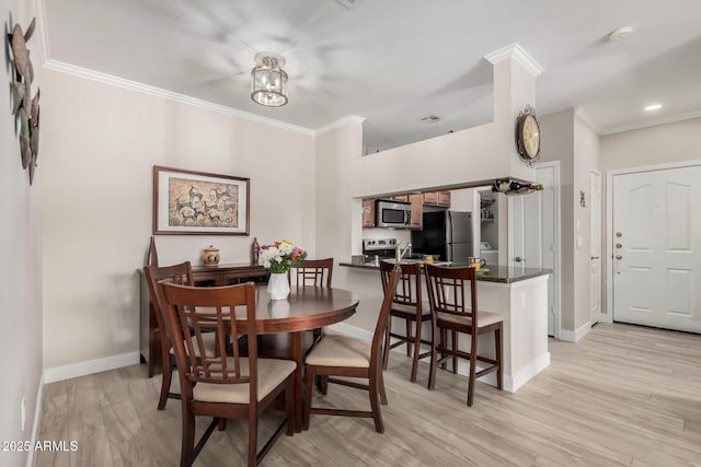 dining space with ornamental molding and light wood-type flooring