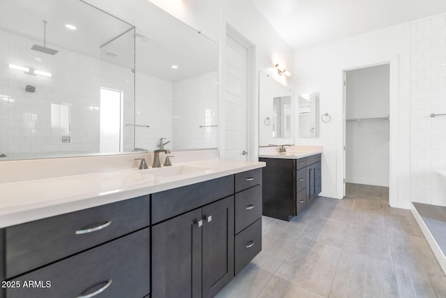 812 E Summerside Rd, Phoenix, AZ 85042 - bathroom featuring a tile shower, two vanities, a spacious closet, and baseboards