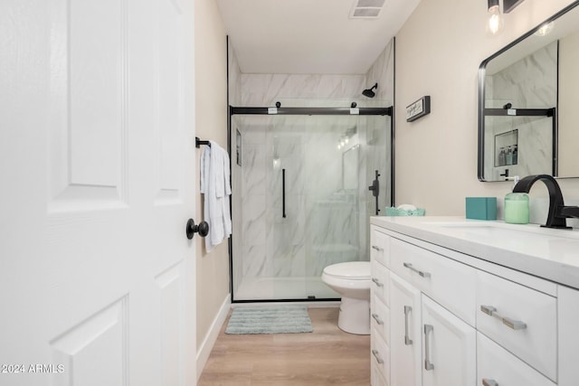 bathroom with hardwood / wood-style floors, vanity, toilet, and walk in shower