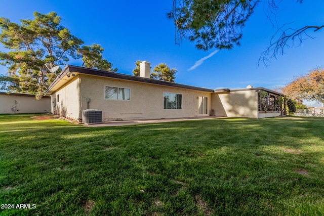 rear view of house featuring a lawn and central AC