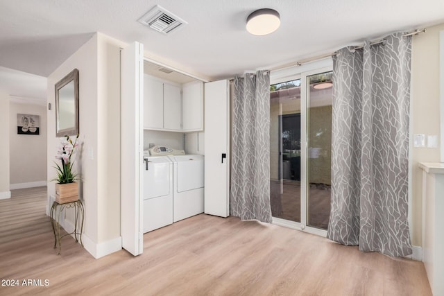 washroom with washer and clothes dryer, cabinets, and light hardwood / wood-style flooring