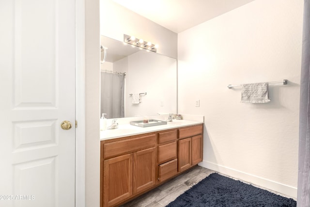 full bath with double vanity, baseboards, and a sink