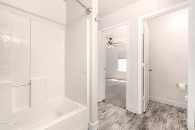 full bathroom with toilet, baseboards, wood tiled floor, ceiling fan, and bathtub / shower combination