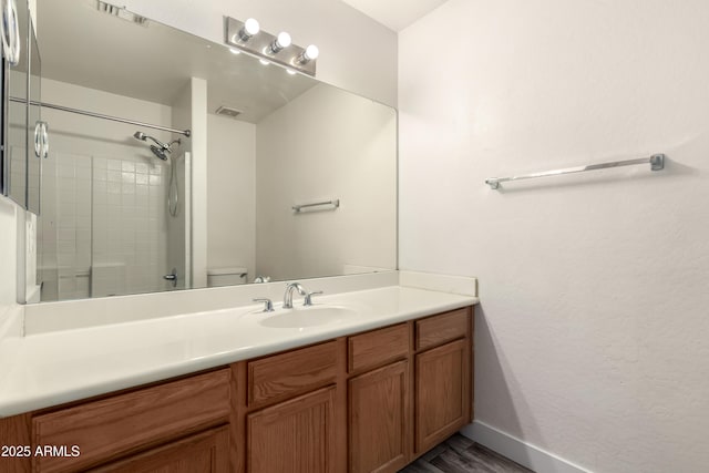 full bathroom with visible vents, vanity, wood finished floors, toilet, and baseboards