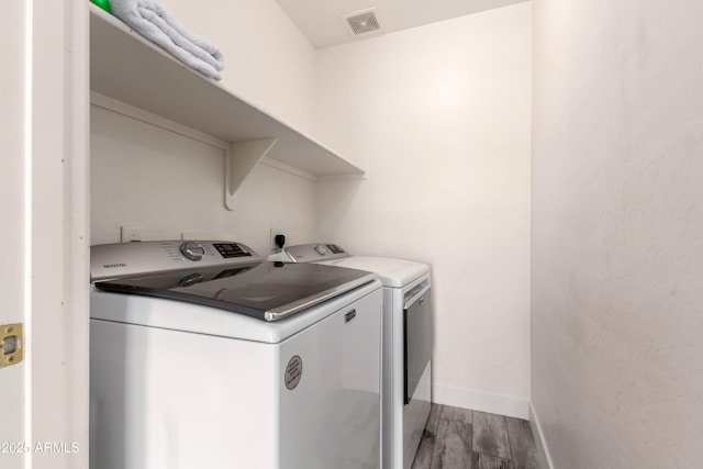 washroom featuring laundry area, separate washer and dryer, baseboards, wood finished floors, and visible vents