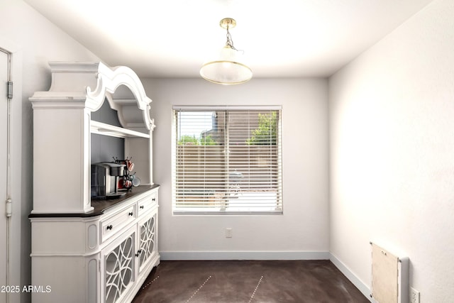 unfurnished dining area with baseboards and concrete floors