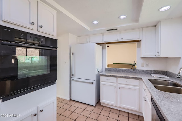 kitchen featuring a tray ceiling, white cabinets, a sink, and freestanding refrigerator