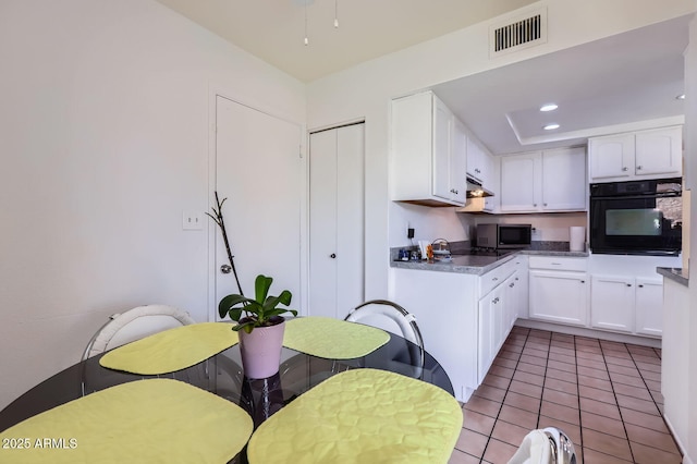 kitchen featuring visible vents, black appliances, and white cabinetry