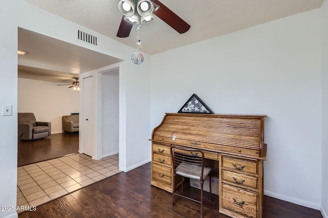 home office featuring baseboards, dark wood-style flooring, visible vents, and a ceiling fan