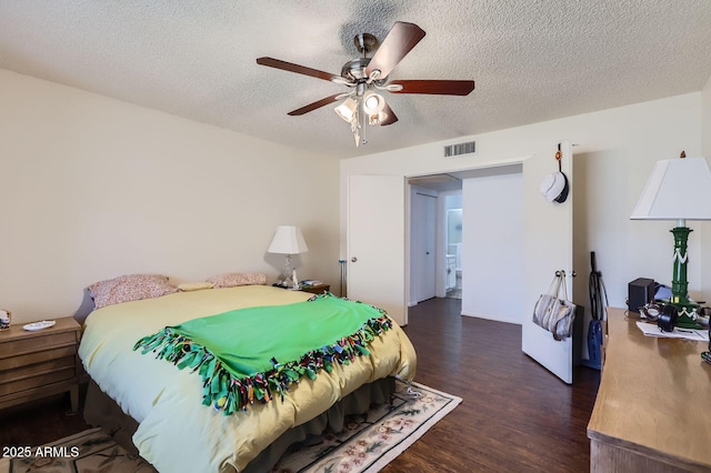 bedroom with a textured ceiling, ceiling fan, dark wood-style flooring, and visible vents