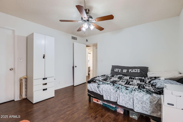 bedroom featuring ceiling fan, a textured ceiling, visible vents, and wood finished floors