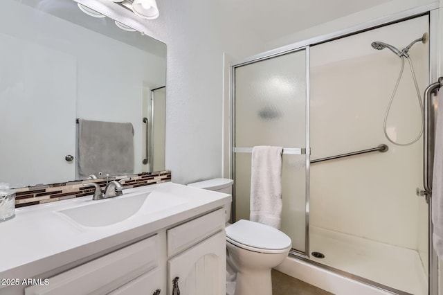 bathroom with toilet, a shower stall, decorative backsplash, and vanity