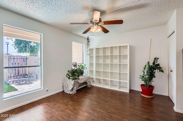 unfurnished room with ceiling fan, a textured ceiling, baseboards, and wood finished floors