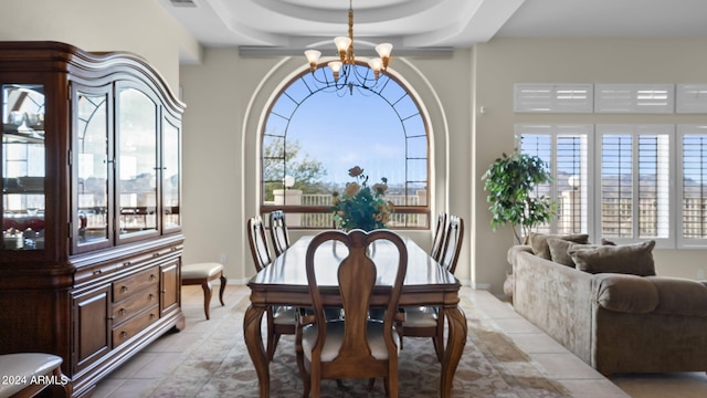 dining area featuring an inviting chandelier, a tray ceiling, and light tile patterned floors