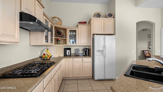 kitchen with light tile patterned floors, sink, black gas cooktop, ventilation hood, and white fridge with ice dispenser