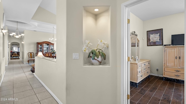 hallway featuring lofted ceiling, dark tile patterned flooring, and a notable chandelier