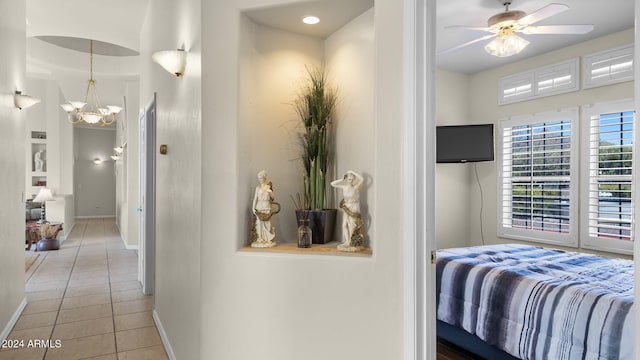 bedroom with ceiling fan with notable chandelier and light tile patterned floors