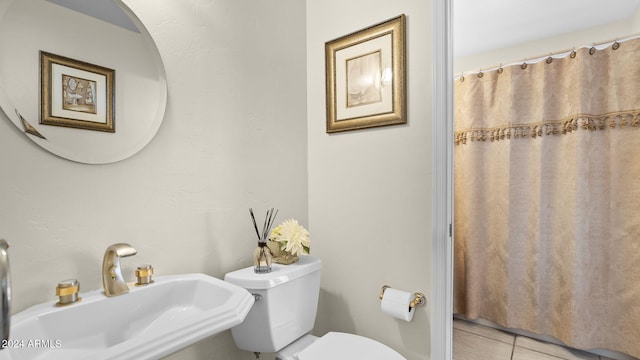 bathroom featuring curtained shower, toilet, sink, and tile patterned floors