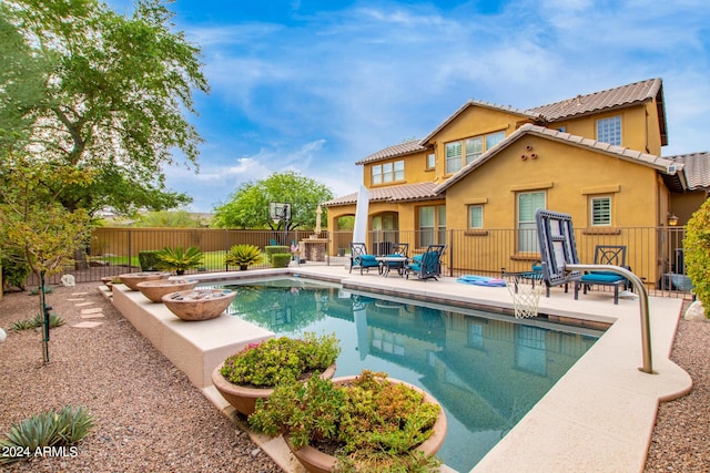 back of house featuring a fenced in pool, a tile roof, stucco siding, a fenced backyard, and a patio