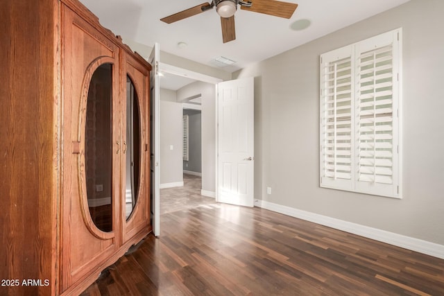 spare room featuring visible vents, baseboards, ceiling fan, and dark wood-style flooring