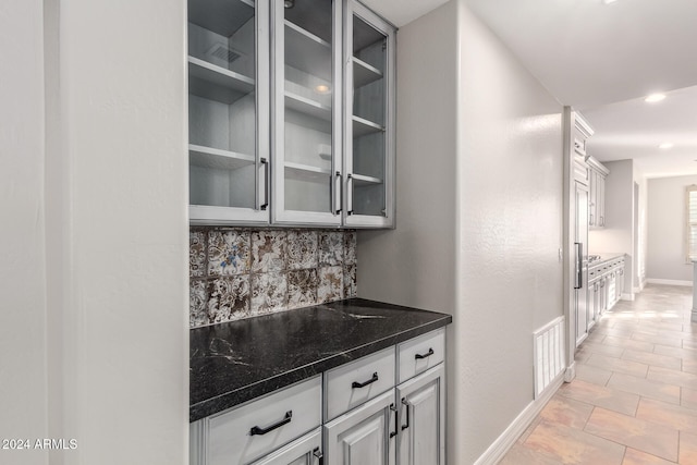 bar with light tile patterned flooring, dark stone countertops, and tasteful backsplash