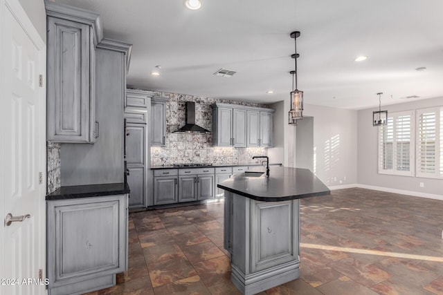 kitchen featuring gray cabinets, wall chimney exhaust hood, dark countertops, a sink, and backsplash