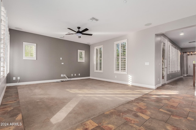 carpeted spare room with visible vents, baseboards, and a ceiling fan