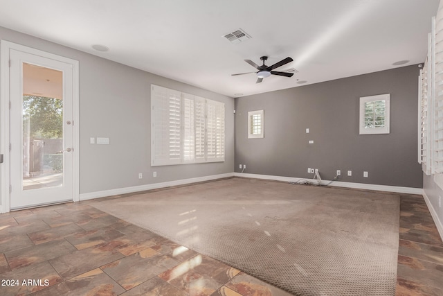 carpeted spare room with visible vents, a ceiling fan, and baseboards